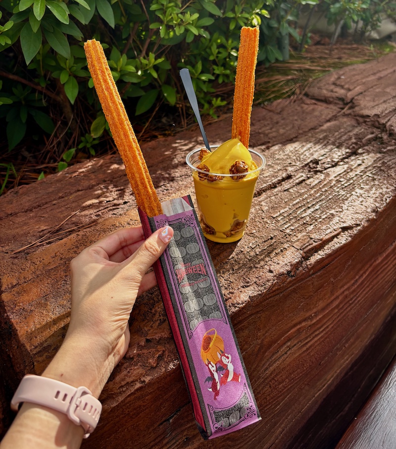 東京ディズニーランドのチュロス（メイプルパンプキン）と、ハロウィーンサンデー（パンプキンソフトクリーム）が並んだ、ディズニー・ハロウィーンの食べ歩きスイーツの写真
